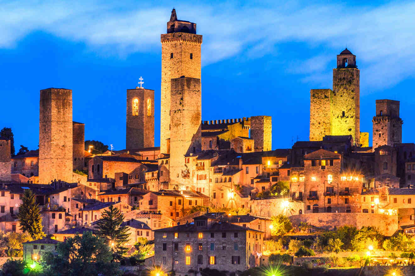 Night view of San Gimignano, Italy, featuring illuminated medieval towers and buildings under a twilight sky.