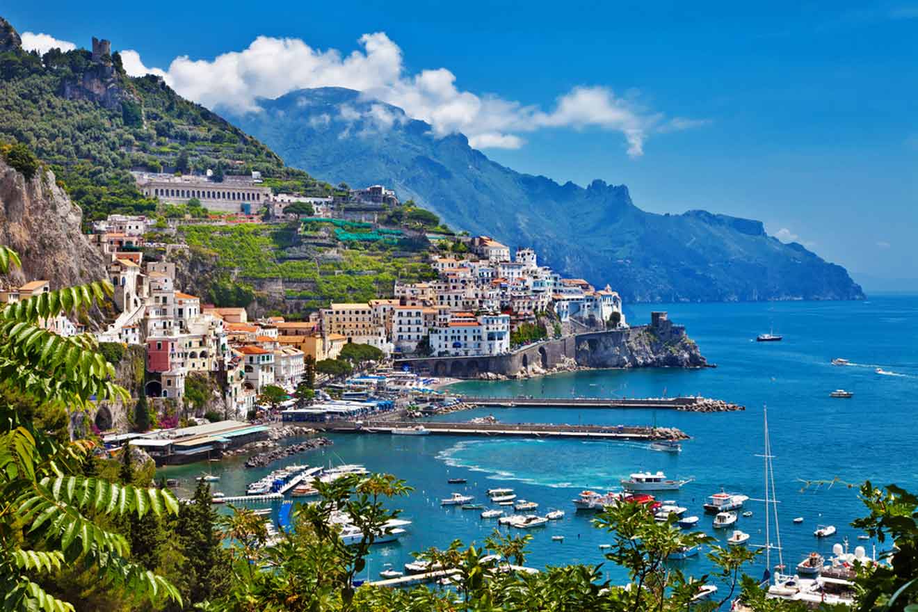 A scenic view of a coastal village with colorful buildings by the sea, backed by rugged cliffs and a clear blue sky.