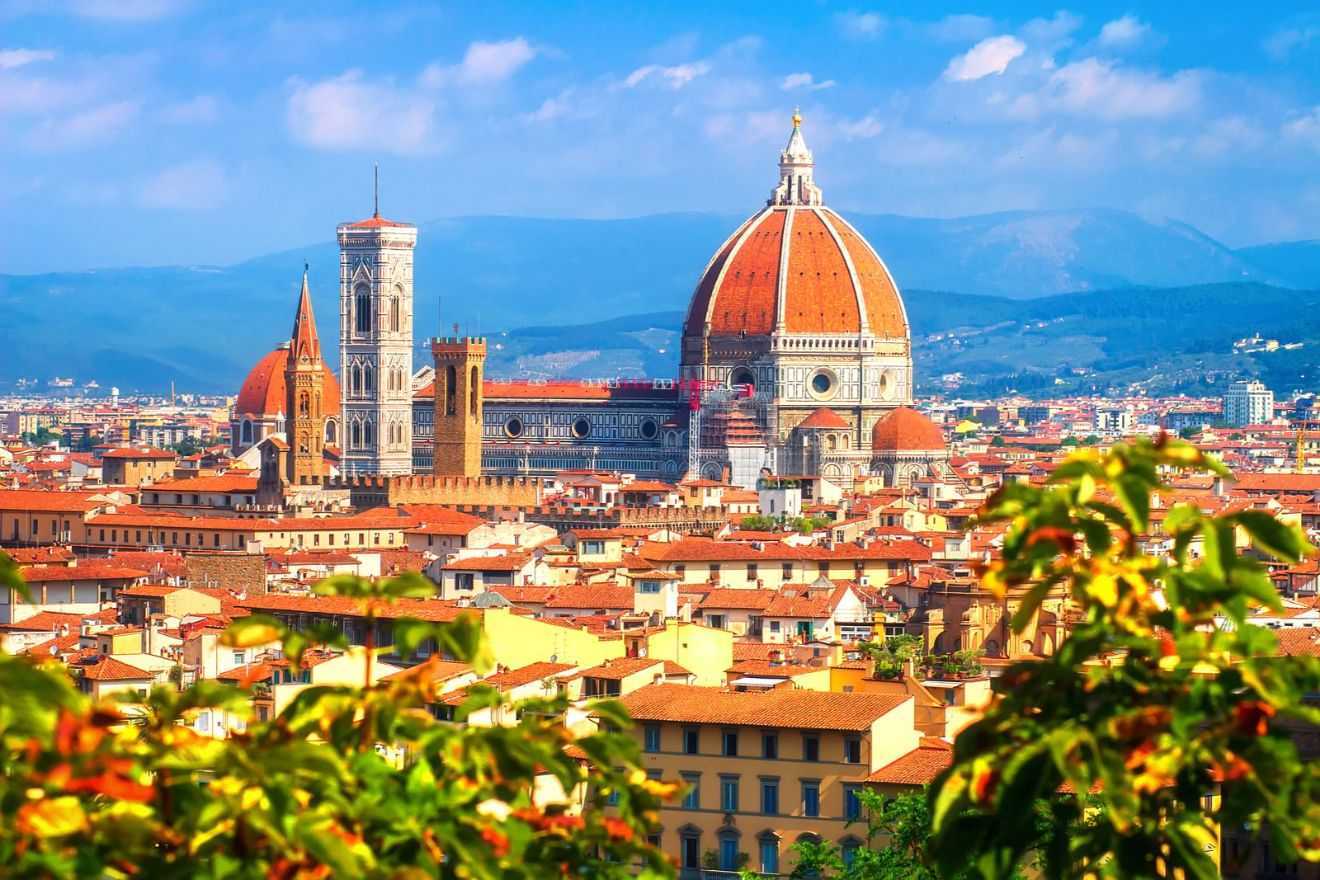 Panoramic view of Florence, Italy, with the Duomo, Giotto's Campanile, and surrounding buildings under a clear blue sky.