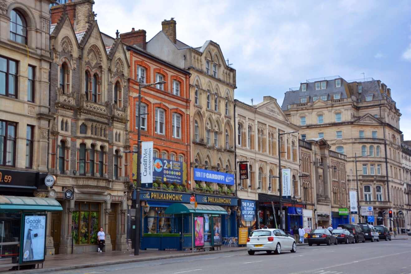 Historic architecture lines the street in Cardiff City Center, with vehicles and pedestrian movement creating a vibrant urban scene