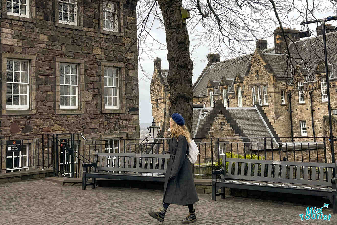 The writer of the post walking down a cobblestone street past a stone building