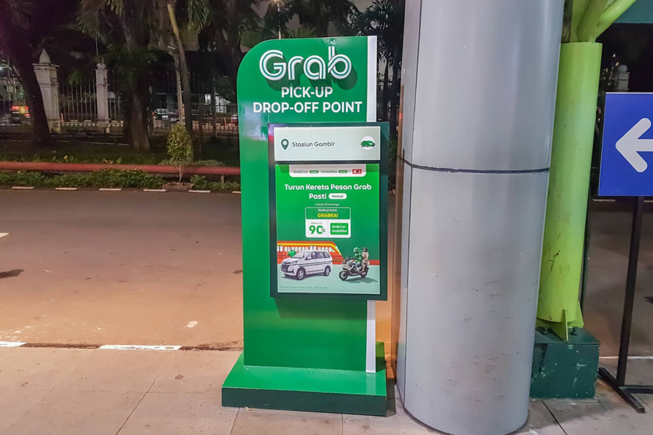 A Grab pick-up and drop-off point sign at a designated area by the roadside, with information and instructions displayed on the sign.