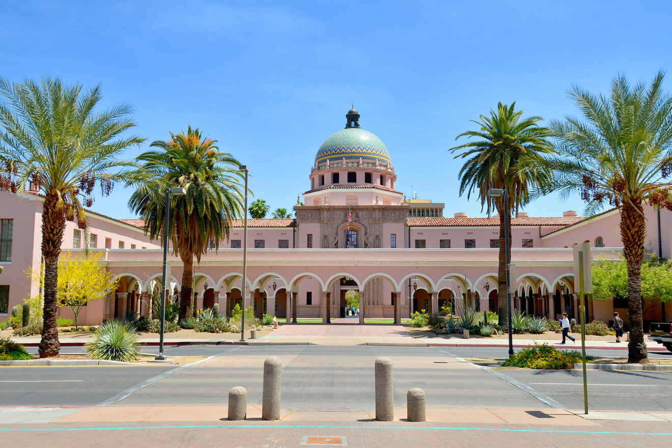 A large building with a colorful dome, arched entrance, and palm trees in the foreground.