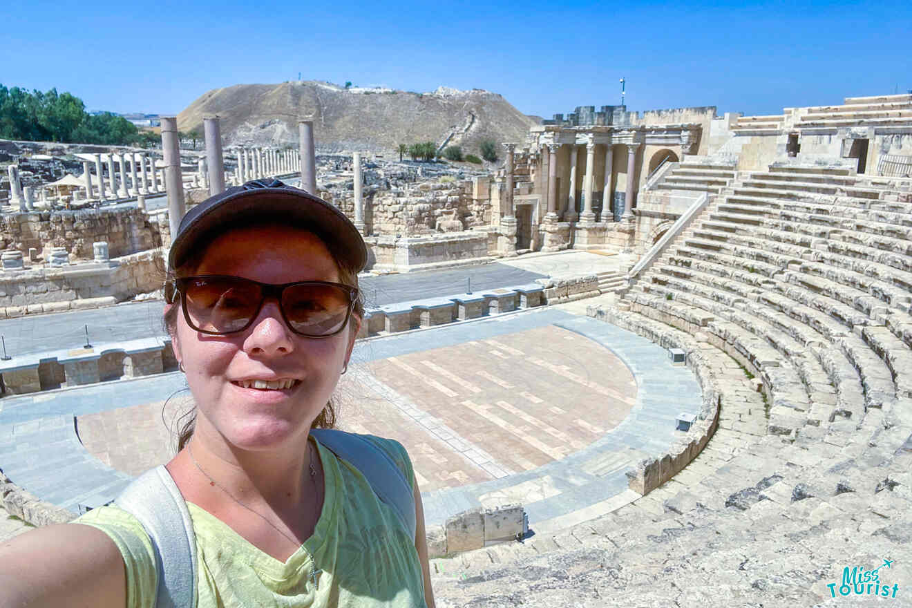 The writer of the post takes a selfie at a historic amphitheater with stone seating and columns under a clear blue sky.