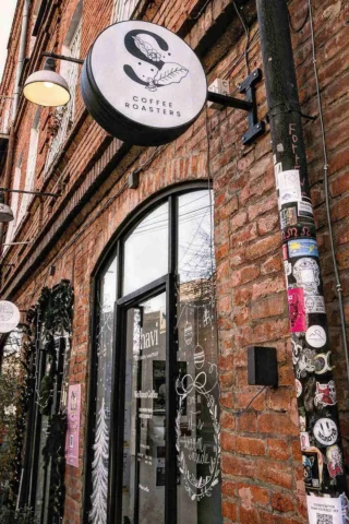 Exterior of a brick coffee shop with a round sign reading 