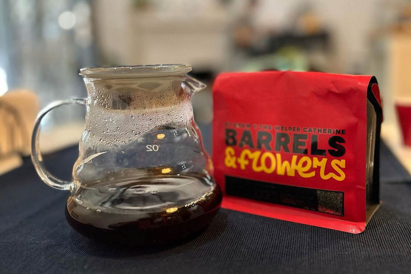 A glass coffee pot filled with dark liquid sits next to a red coffee bag labeled 